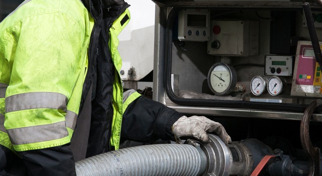 Der Fahrer achtet auf die richtige Befestigung des Schlauchs am LKW, um Pellets ins Lager einzublasen.
