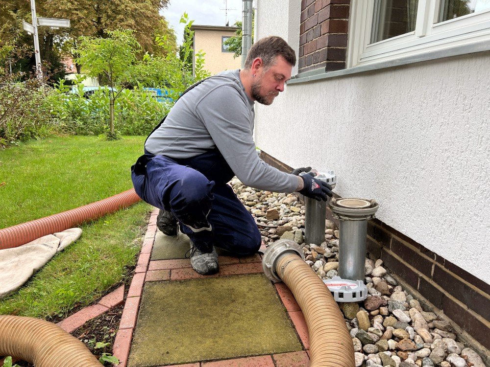 Der Pelletfahrer in Latzhose bringt die Schläuche zum Einblasen der Pellets an den Stutzen an.