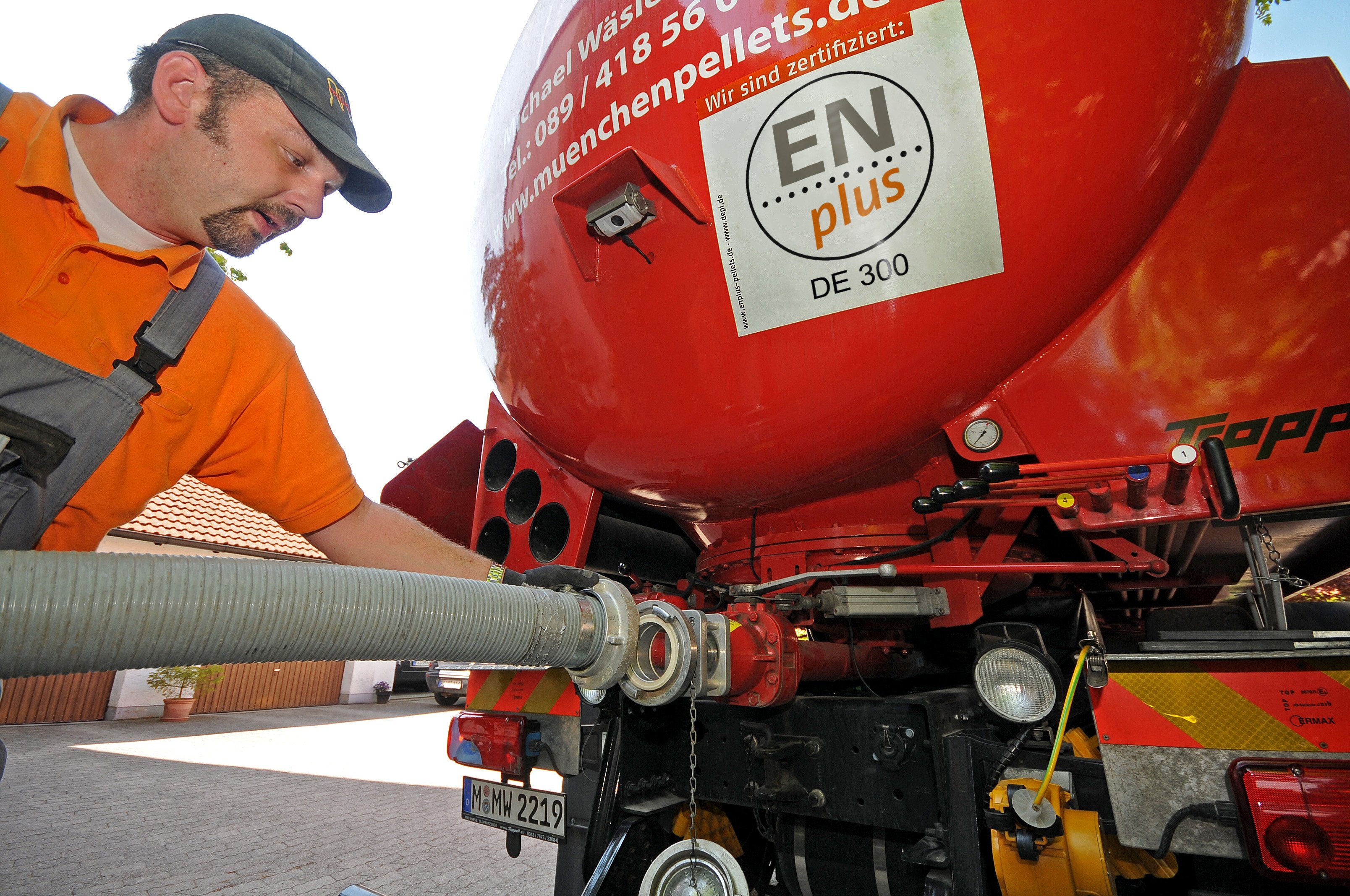 EIn Mann befestigt einen Schlach am Heck eines roten Lkw