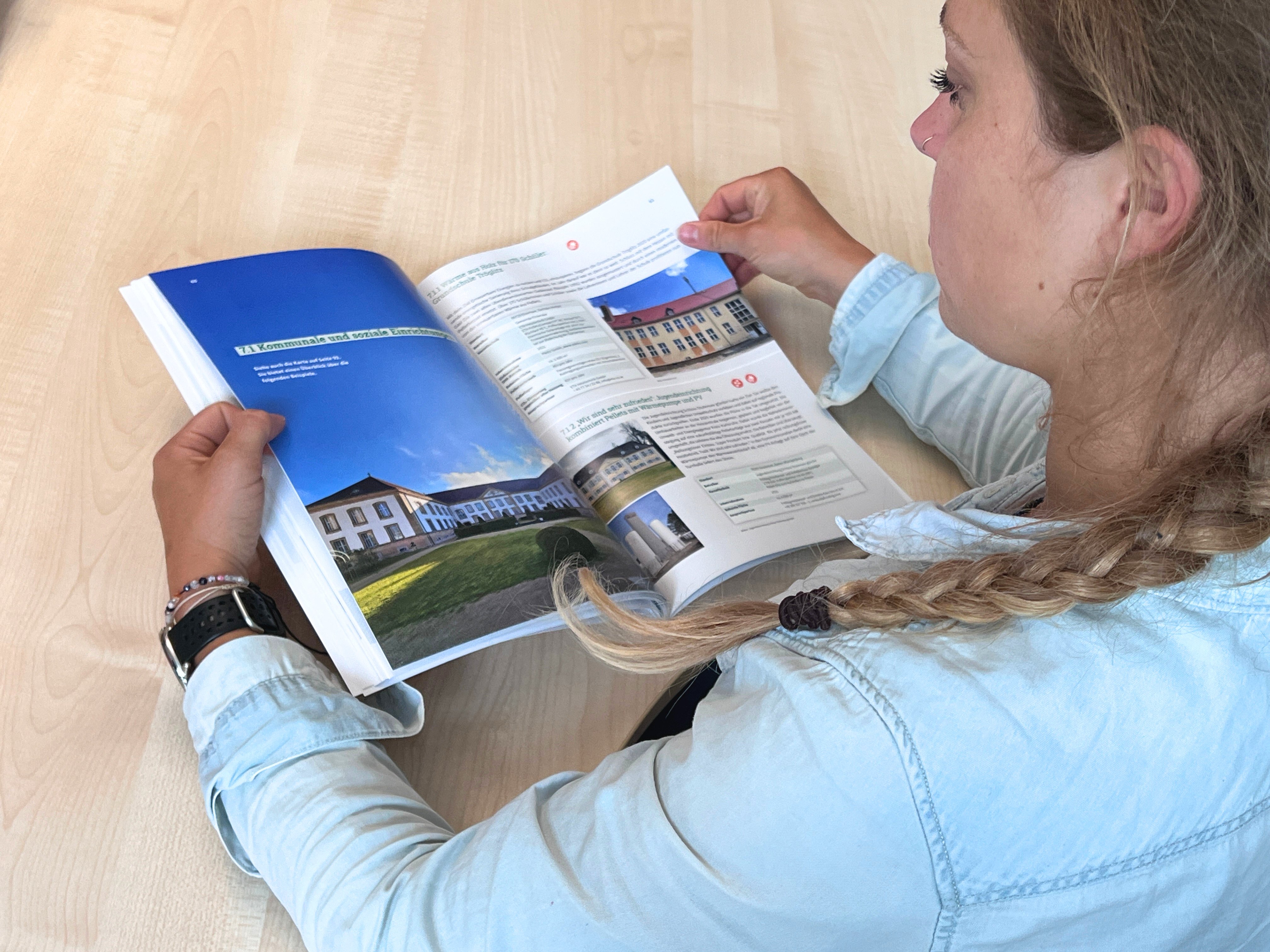 Frau blättert in einer Broschüre. Blöick über ihre Schulter.