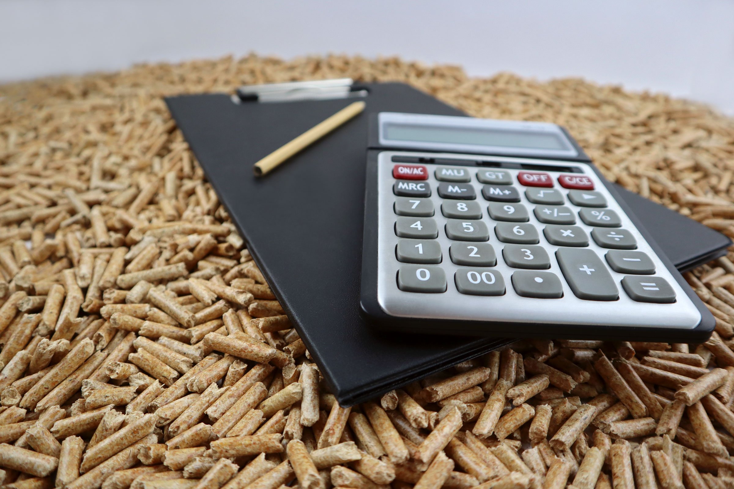 Ein Taschenrechner und ein Klemmbrett liegen auf einem Hintergrund aus losen Pellets, aufgenommen ist das Bild von schräg unten