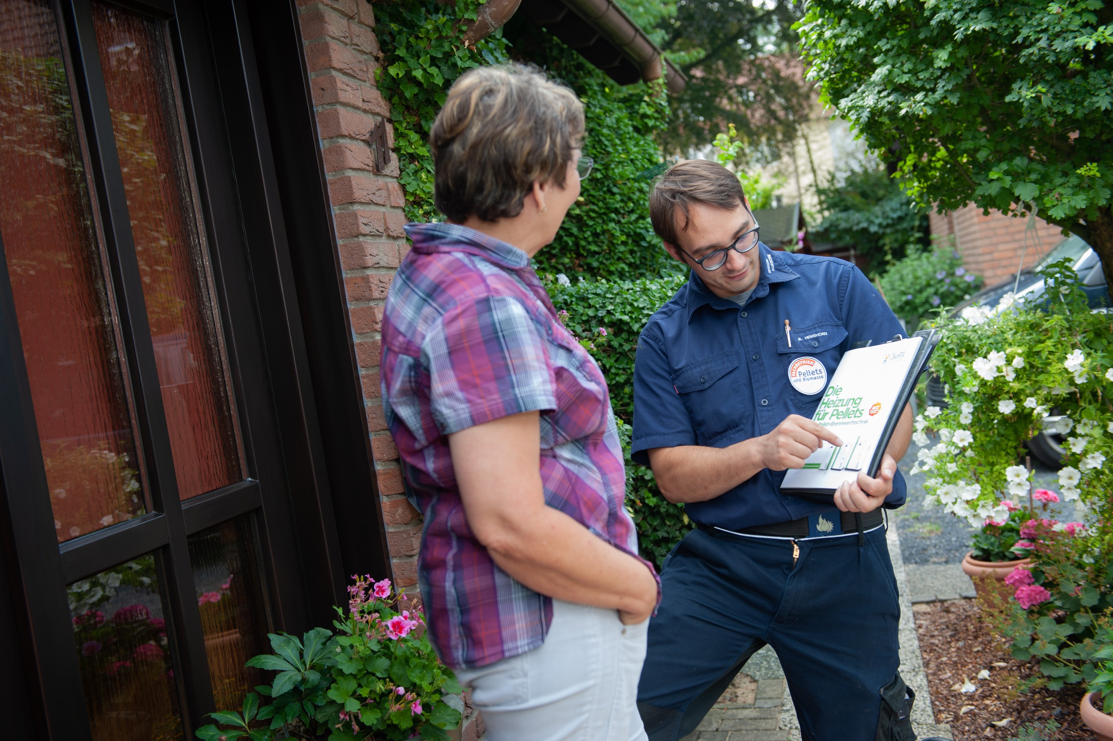 Frau und Mann im Gespräch. Der Mann erklärt der Frau etwas auf einem Klemmbrett