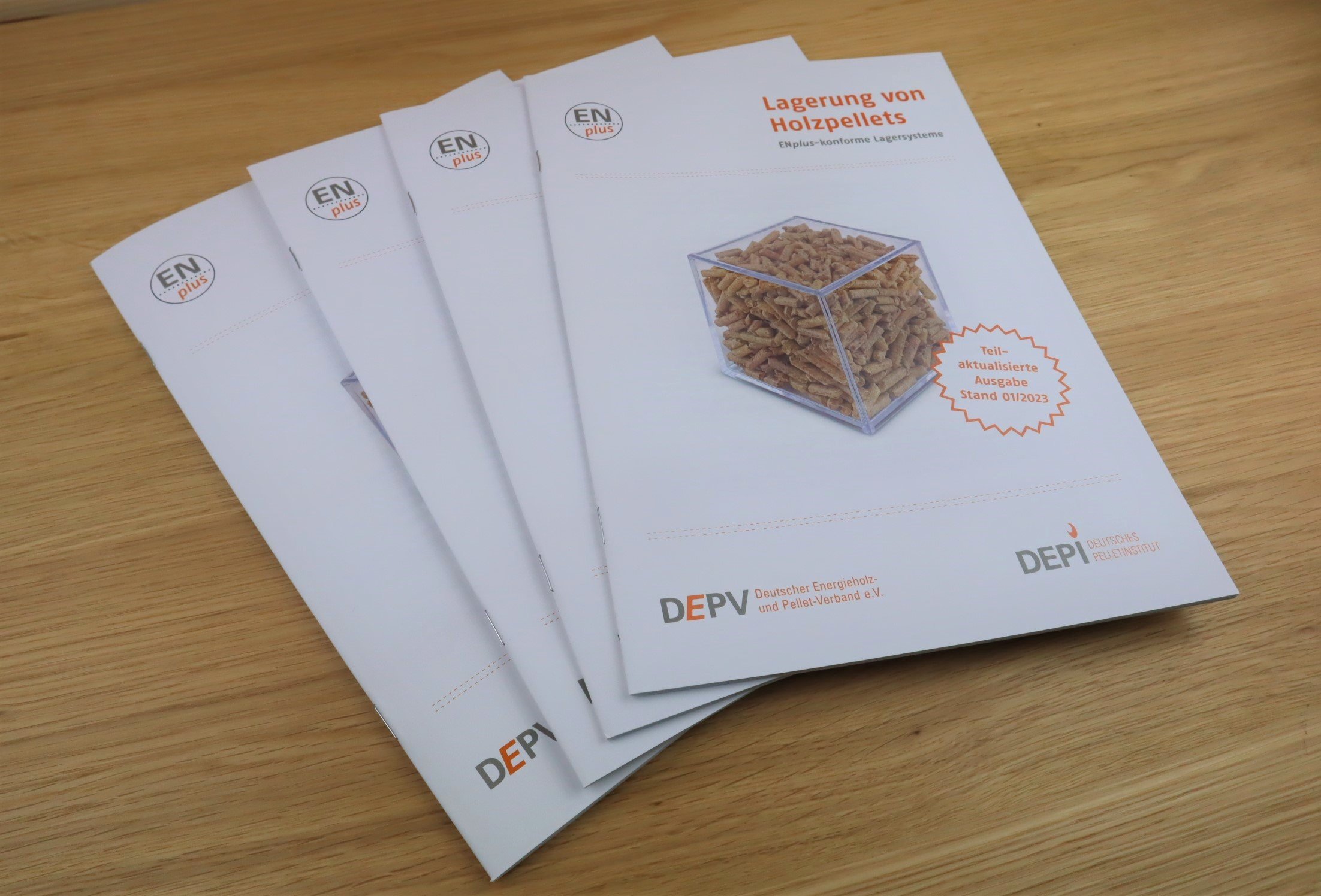 Vier Exemplare der Broschüre Lagerung von Holzpellets aufgefächert auf einem Tisch