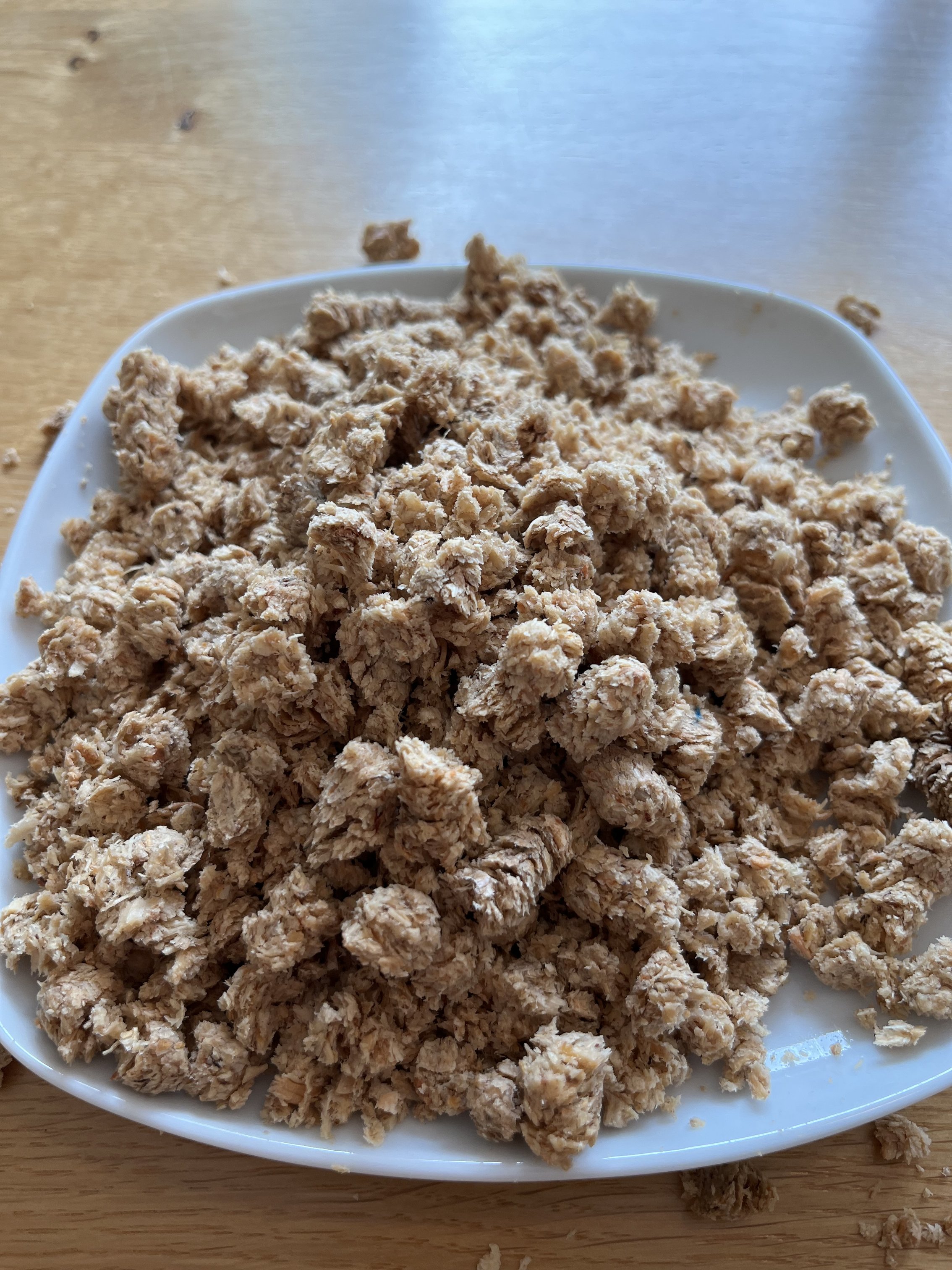 Auf einem Teller sind aufgequollene Pellets. Sie haben teilweise ihre zylindrische Form verloren und sind zerbröselt.